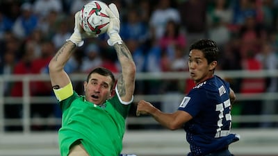 Uzbekistan's goalkeeper Ignatiy Nesterov, left, saves the ball against Muto. AP Photo