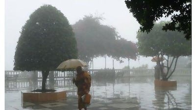 A monk in saffron robes crosses the grounds of Doi Suthep amid an afternoon thunderstorm. Effie-Michelle Metallidis for The National
