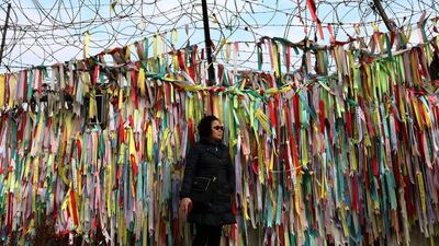 A woman stands in front of prayer ribbons wishing for reunification of the two Koreas in Paju, South Korea. Getty Images