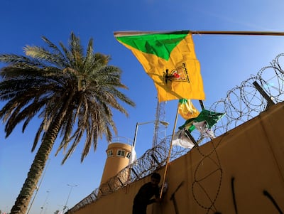 A protester waves the flag of Kataib Hezbollah, an Iran-backed Iraqi militia, outside the US embassy in Baghdad. Reuters