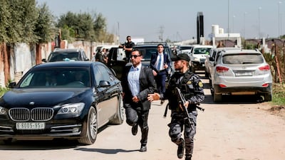 A bodyguard of the Palestinian Prime Minister (centre) and a Hamas security officer (right) escort the PM's convoy as he leaves Gaza City on March 13, 2018. Mahmud Hams / AFP