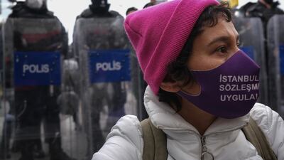 A protester wears a face mask written 'Apply Istanbul Convention' as she shouts slogans while Turkish riot police block the way during a protest against Turkey's decision to withdraw from the Istanbul Convention on March 31, 2021. EPA