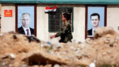 A Syrian soldier loyal to President Bashar Al Assad walks in front of posters of Mr Al Assad and President Putin. Omar Sanadiki / Reuters