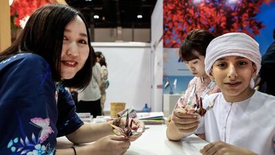 Kyoka Ono, 21, teaches Ahmed Al Hosani, 12, the Japanese art of Origami at the Adihex exhibition. Victor Besa / The National