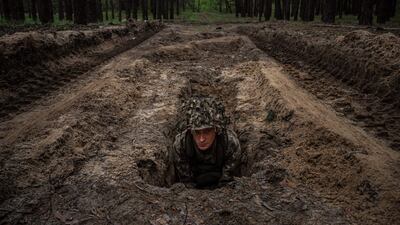 A Ukrainian soldier lies in a trench during a military exercise in the Kharkiv region. AFP
