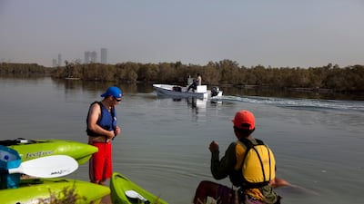 A developer company's motor boat passes by kayakers in the Eastern Mangroves near the East Road. (Silvia Razgova/The National)
