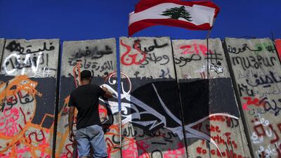 A Lebanese activist paints graffiti on a concrete wall installed by authorities a day before near the main government building in downtown Beirut on August 25, 2015. Shortly after, the wall was taken down on orders from the prime minister, likely as a move to appease demonstrators who dubbed it a "wall of shame". Hassan Ammar/AP Photo