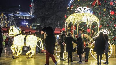People enjoy a market as Christmas decorations illuminate the main boulevard in downtown Tirana, Albania. EPA