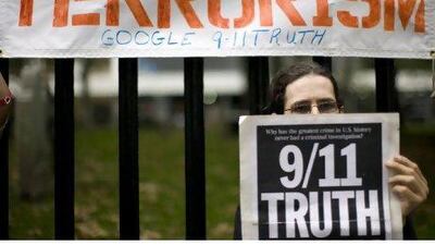 A demonstrator holds a banner next to the former World Trade Center site during ceremonies marking the seventh anniversary of the September 11 attacks in New York September 11, 2008. REUTERS/Eduardo Munoz (United States)