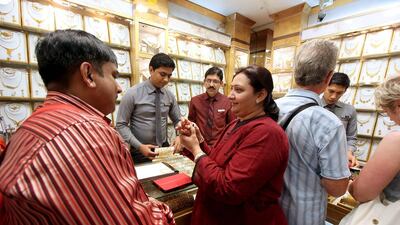 Indian tourists Vikram Mehta, left, and his wife Priti buy jewellery in one of the shops at Gold Souk in Dubai. Pawan Singh / The National