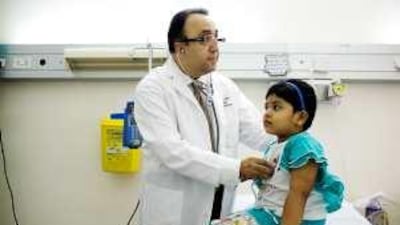Dr Taisser Atrak, the chair of pediatrics at the Marfaq Hospital checks Sharon Biby, 4, before she has her tonsils removed.