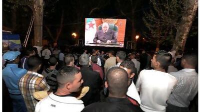 People look at Algerian President Abdelaziz Bouteflika delivering a speech on a giant screen, at Amir Abdelkader square in Telemcen on April 15, 2011. Bouteflika announced, in a speech to the nation, an upcoming revision of the Algerian constitution which will strengthen the democracy. AFP PHOTO / FAROUK BATICHE