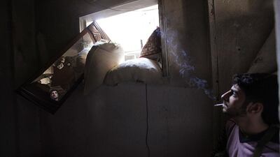 A Free Syrian Army fighter smokes while monitoring an area through a mirror inside a room in Deir al-Zor, Syria. Khalil Ashawi / Reuters