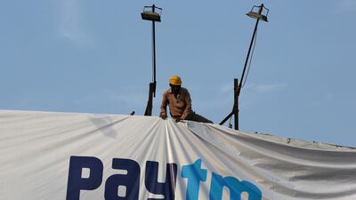 A worker adjusts a hoarding of Paytm in India. The company's investors include Berkshire Hathaway, SoftBank Group and Ant Group. Reuters