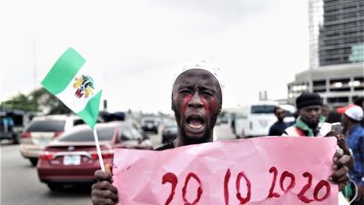 A protester holds a placard with an inscription bearing the date of first protest against police brutality. EPA