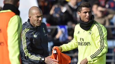 Real Madrid’s Portuguese forward Cristiano Ronaldo, right, gives a bib to Real Madrid’s new French coach Zinedine Zidane during his first training session as coach of Real Madrid at the Alfredo di Stefano stadium in Valdebebas, on the outskirts of Madrid, on January 5, 2016. Gerard Julien / AFP