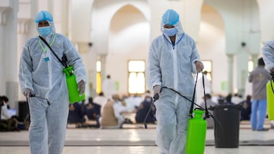 Health workers wearing personal protective equipment disinfect the floor inside the mosque. REUTERS