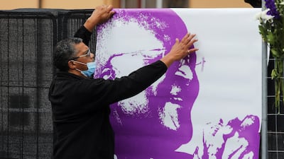 A man hangs a poster of Tutu on the day of his funeral service in Cape Town, South Africa. Reuters