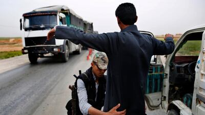 In this March 28, 2018 photo, a Kurdish policeman checks an Arab Syrian man at a checkpoint controlled by The US-backed Syrian Democratic Forces, SDF, on a highway in Hassakah province, Syria. AP