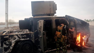 A Houthi rebel inspects a burnt armoured vehicle. AFP