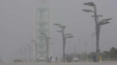 Volunteers walk in front of the Olympic studio tower at the Olympic Green in Beijing.