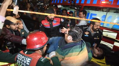 Pakistani policemen and volunteers move an injured blast victim from a blast site after a powerful explosion in Lahore on February 13, 2017. AFP / ARIF ALI