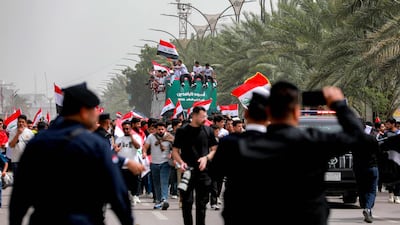 Members of Iraq's team sit atop an open-top bus as they greet fans along the Jadriya area of central Baghdad. AFP