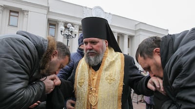 Ukrainian believers of the Ukrainian Orthodox Church of the Moscow Patriarchate kiss hands of a priest during their praying in front of the parliament building in Kiev. EPA