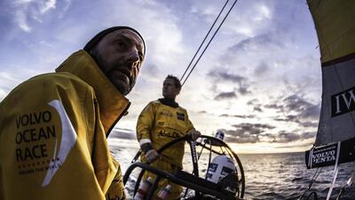 A backlit Ian Walker eyes the sail trim as Luke Parkinson drives at sunset over the Atlantic Ocean. Matt Knighton / Abu Dhabi Ocean Racing / Volvo Ocean Race