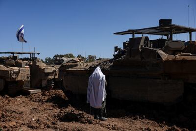 An Israeli soldier praying next to military vehicles near the Israel-Gaza border. Reuters