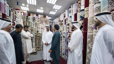 Sheikh Mohammed bin Zayed speaks with staff at Al Safa Carpet shop, in the carpet market of the Mina Zayed Port. Seen with Jassem Al Zaabi, Chairman of Abu Dhabi Executive Office and Abu Dhabi Executive Council Member (L), Mohammed Al Mazrouei, Undersecretary of the Crown Prince Court of Abu Dhabi (2nd R), and Sheikh Theyab bin Mohammed, Chairman of the Department of Transport, and Abu Dhabi Executive Council Member (R). Ryan Carter for the Crown Prince Court - Abu Dhabi