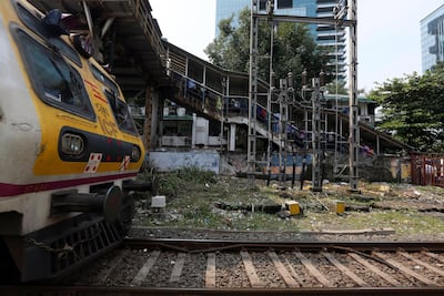 Commuters walk on foot overbridge as the local train passes by at Elphinston Road railway station in Mumba. EPA