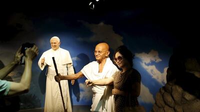 A woman poses for photos on July 30, 2015, with the wax figures of Mahatma Gandhi, centre, and Pope Francis, left, at Grevin Wax Museum in Seoul, South Korea, July 30, 2015. French wax museum Musee Grevin has opened its first Asian branch in central Seoul. Kim Hong-Ji / Retuers