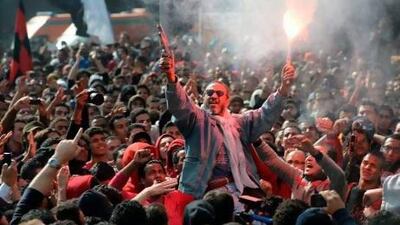 An Egyptian fan of Al Ahly football club fires celebratory shots in the air and lights a flare as club supporters celebrate outside its headquarters in Cairo on Saturday after a court sentenced 21 people to death over a football riot that killed more than 70 people last year. Khaled Desouki / AFP