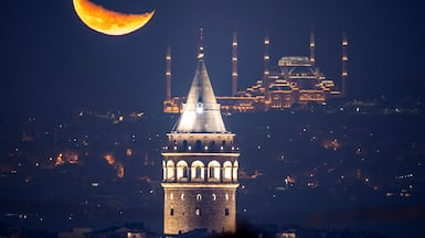 The crescent moon rises behind Istanbul's Camlica mosque and Galata tower. AP