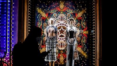 A man walks past a shop window adorned with Christmas lights, in Milan, Italy. AP Photo