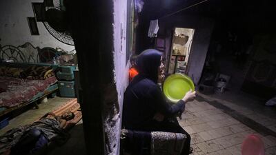 A Palestinian woman uses a plastic tray to cool herself down on a hot day during a power cut as a boy sleeps inside their house that is illuminated by battery-powered lights after Gaza's lone power plant shut down amid tension with Israel, in Jabalia refugee camp, in the northern Gaza Strip. Reuters