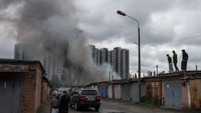 Local residents watch smoke rising above garages following an air attack in Kyiv. AFP