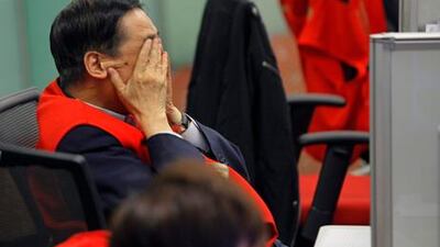 A trader reacts at the Hong Kong Stock Exchange where stocks took another battering, amid renewed fears over Greece. Vincent Yu / AP Photo