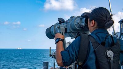 A US Navy personnel member looking through binoculars from the starboard bridge wing of the guided-missile cruiser USS Shiloh during a Strait of Hormuz transit with the guided-missile cruiser USS Monterey, on July 25. (Rawad Madanat/US NAVY/AFP).