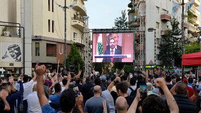 Protesters react as they watch a televised speech by Mr Hariri. EPA