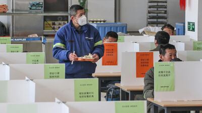 Workers have lunch at a dining hall using boards to separate people to prevent the spread of the new coronavirus in Yantai in China's eastern Shandong province. AFP