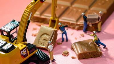 Workmen use a digger and shovels to lift up a square of chocolate. The caption beneath the image reads: "Very good business in the chocolate trade". Courtesy Omar Maree Humaid