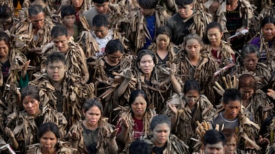 Devout Catholics, dressed in dried banana leaves and smeared with mud, participate in mass at the church