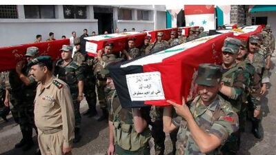 Syrian soldiers carry the coffins of comrades killed in recent violence, during their funeral procession at the military hospital in Homs. AP Photo / SANA