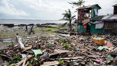 Residents walk past a house damaged during Typhoon Phanfone in Tacloban, Leyte province in the central Philippines. AFP