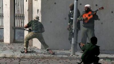 A musician strums his guitar as rebels fire at the Libyan dictator Muammar Qaddafi's troops in the town of Sirte in October 2011. Aris Messinis / AFP