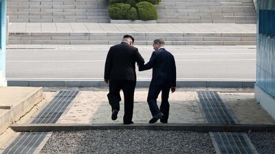 The Korean leaders step over the demilitiarized zone during their historic meeting in April. EPA