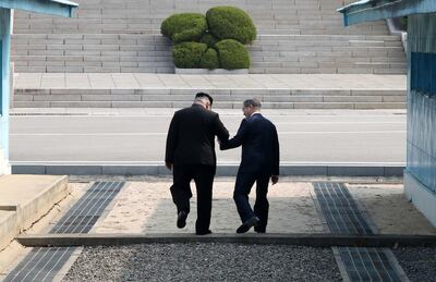 The Korean leaders step over the demilitiarized zone during their historic meeting in April. EPA