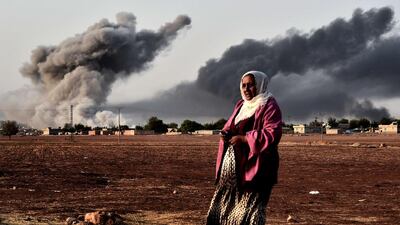 Smoke rises behind a woman in Kobani after an airstrike against the militant group ISIL on Monday. Aris Messinis / AFP